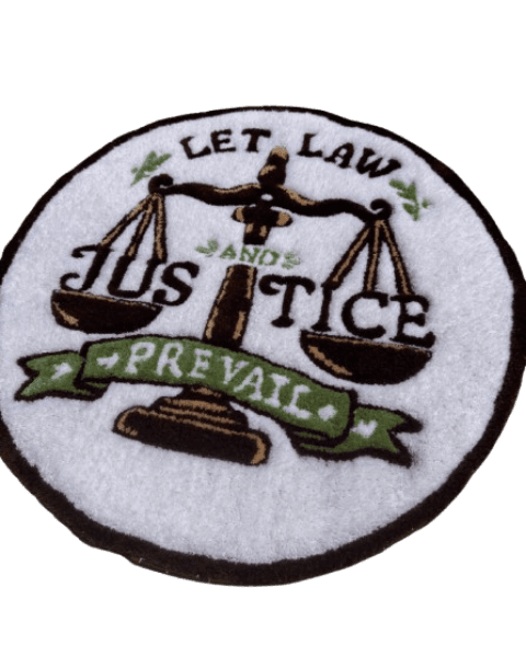 A hand-tufted rug in crisp white featuring a vintage emblem-style scales-of-justice design, with 'Let Law and Justice Prevail' lettered in bold brown and framed by a green banner. A meaningful custom piece — a great gift for a lawyer, law student, or law office.