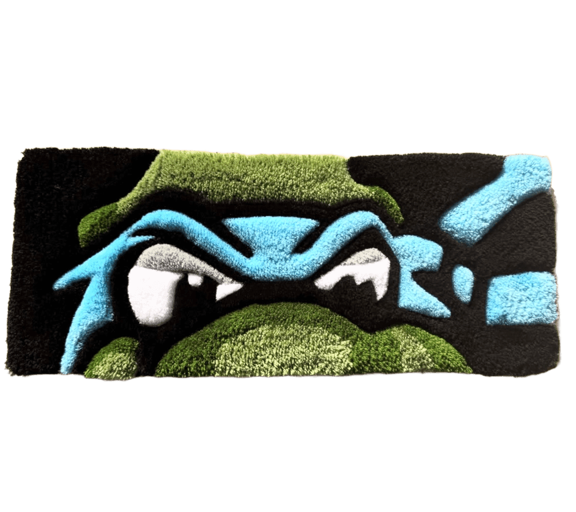 A playful, hand-tufted desk rug sized for a keyboard and laptop setup. A sharp-toothed green and blue monster face in bold contrast against black gives an everyday desk a distinct, unmistakable personality.